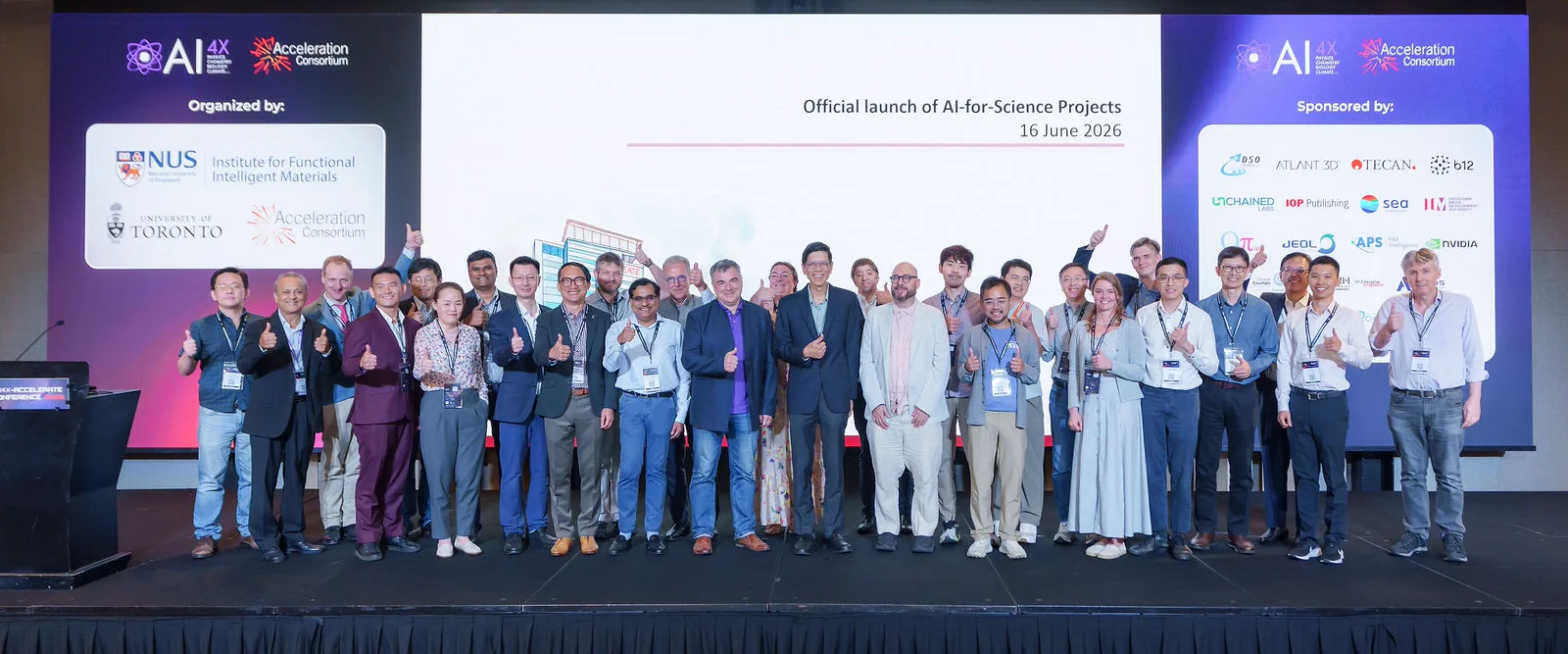 Group of AI4X 2026 participants on stage giving a thumbs-up in front of a screen announcing the official launch of AI-for-Science projects