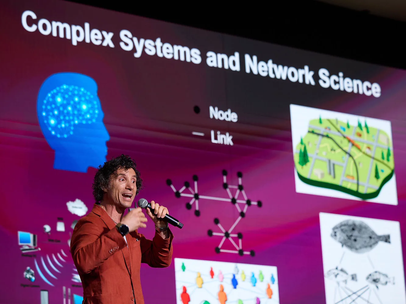 Speaker presenting a slide on complex systems and network science at AI4X 2026